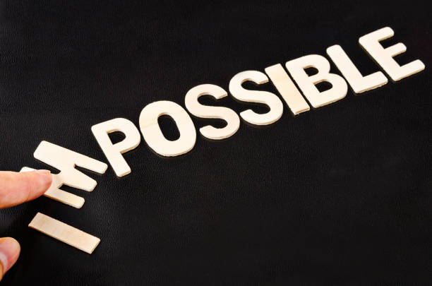 man hand spelling the word impossible from wooden letters, taking out the letter I, M so it written possible. success and challenge concept.